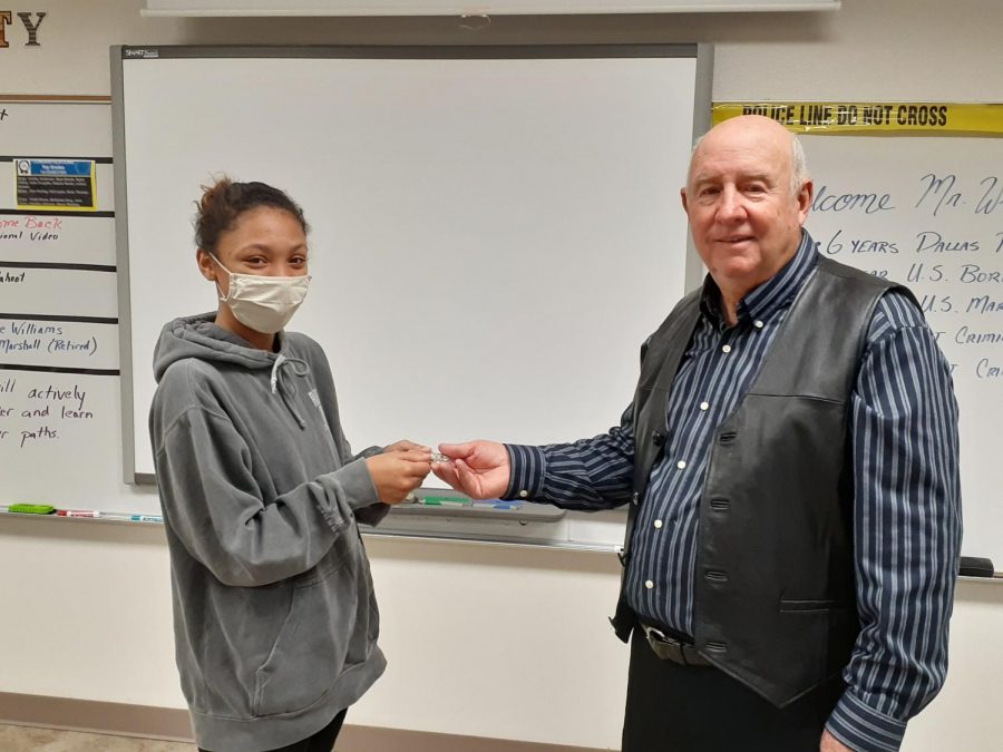 Senior Abinie Prarson handing Dale Williams first responder appreciation coin 